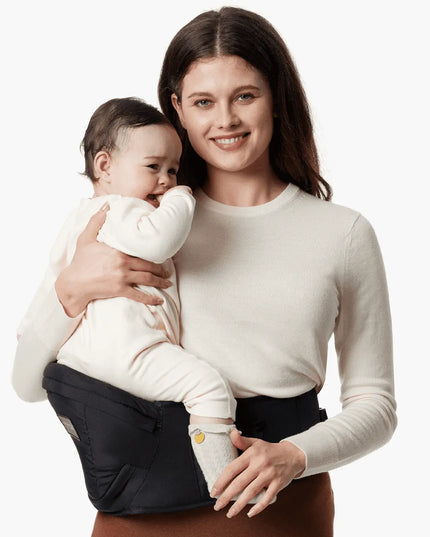 Woman holding a baby in a sling against a white background