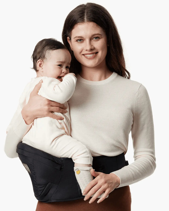 Woman holding a baby in a sling against a white background