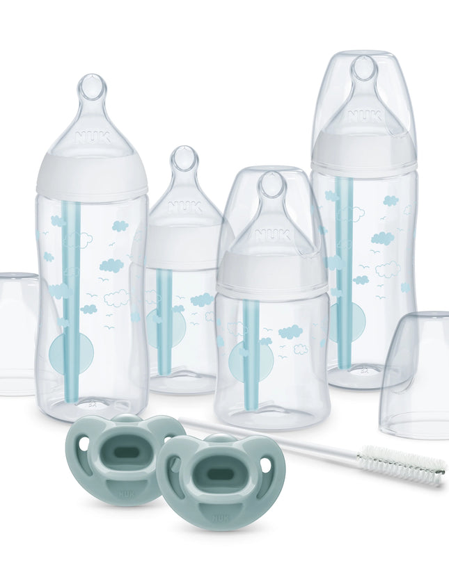 Collection of baby bottles, pacifiers, and a brush on a white background