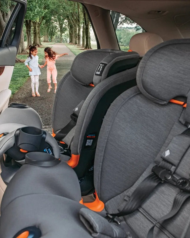 Car interior with gray car seats and a cup holder, showing a view of children playing outside.