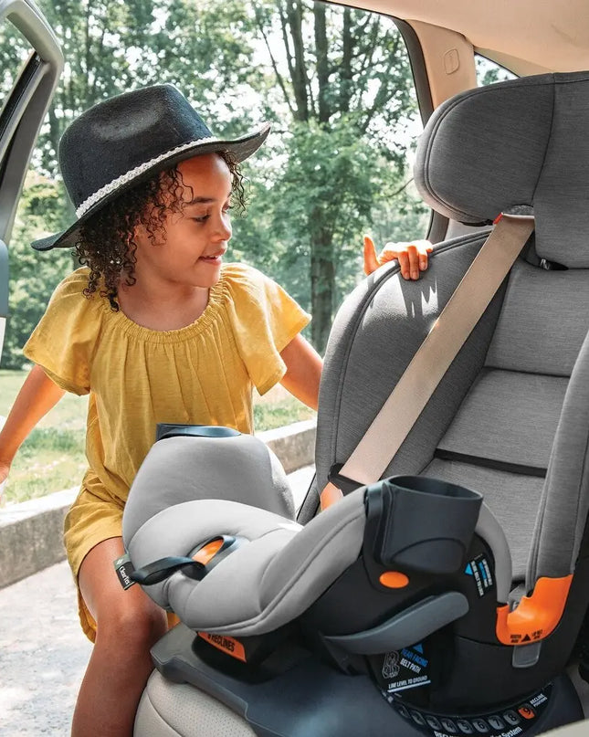 Child in a yellow shirt and black hat interacting with a car seat in a vehicle.