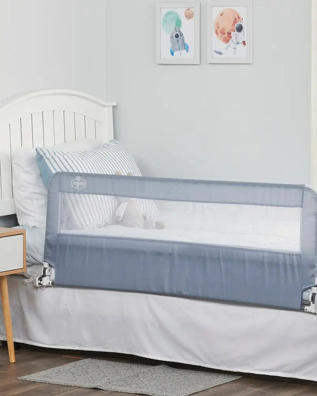 Children's bed with a gray safety rail in a room with a white wall and framed pictures.