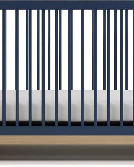 Navy crib with white mattress on a white background