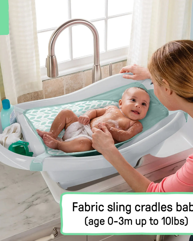 Baby being bathed in a fabric sling with a woman in a bathroom setting.