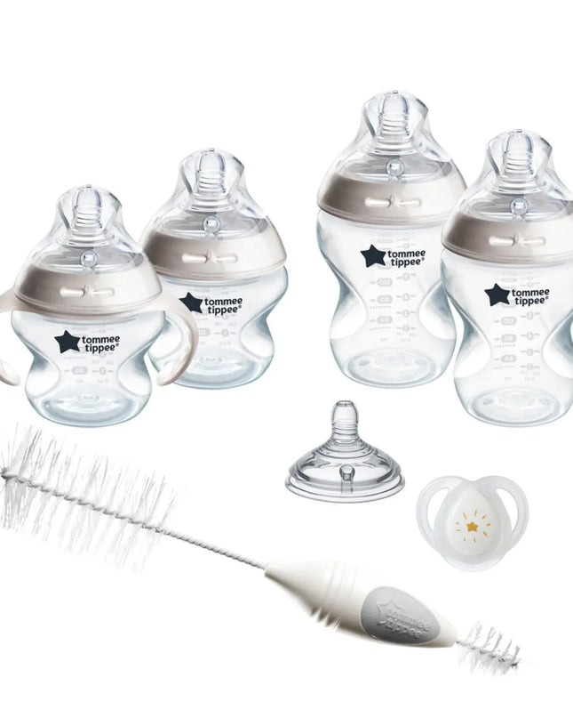 Collection of Tommee Tippee baby bottles, pacifier, and cleaning brush on a white background