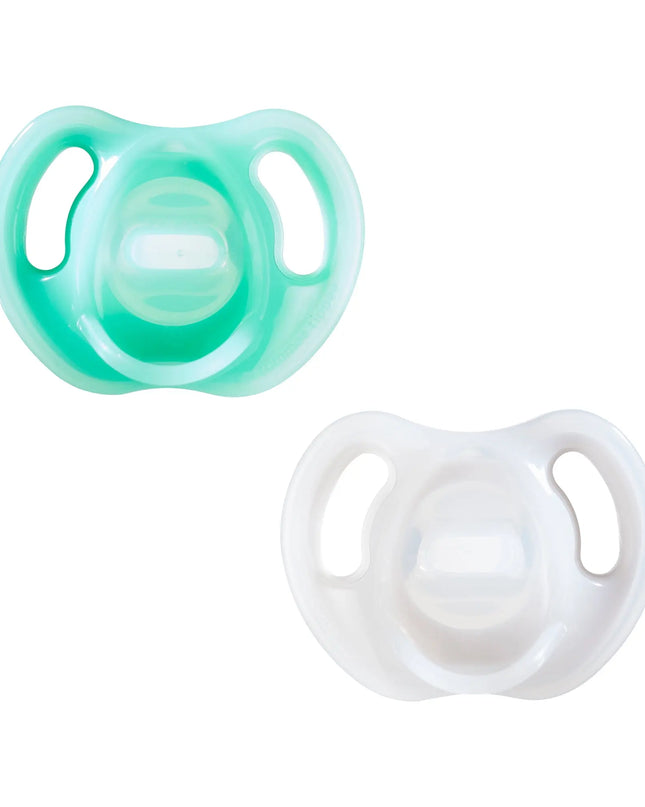 Two baby pacifiers, one green and one white, on a white background