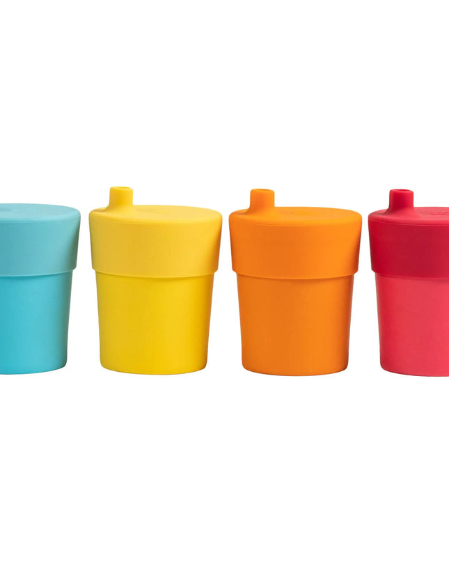 Four colorful sippy cups in blue, yellow, orange, and red on a white background