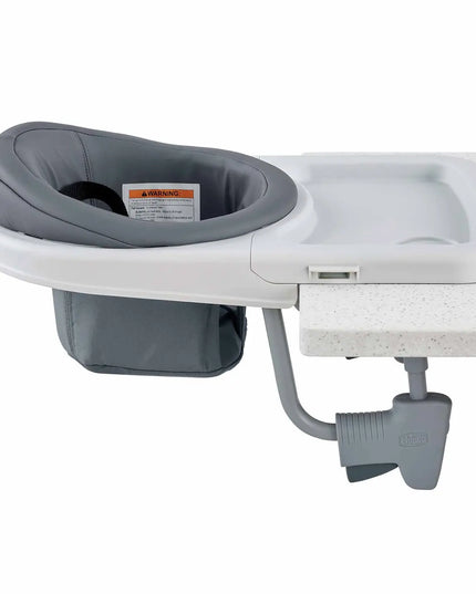 Gray baby booster seat attached to a white countertop on a white background