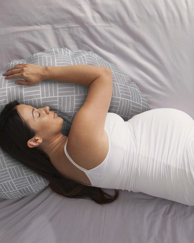 Woman lying on a gray and white patterned pillow on a bed.